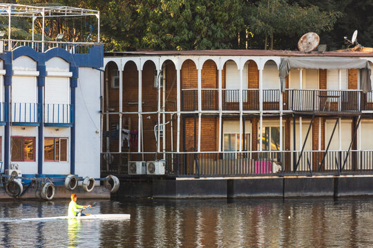 Cairo, Egypt - 8 February 2022: People kayaking on the Nile and houseboats in Zamalek district in golden hour