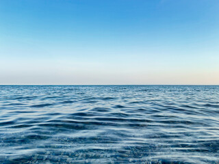 Calm sea under a blue sky at sunrise. calm colors. waterline. waves. ripples. sea water surface. 