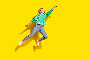 Full length photo of cheerful pretty lady dressed green sweatshirt jumping high rising fist empty space isolated yellow color background