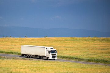 White chinese truck on a road moving in a field