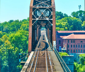Aerial View of Rusted Railroad Bridge and Industrial Building in Lush Landscape
