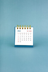 June 2025 white desk calendar on blue background.