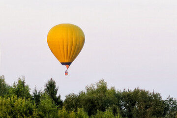 Obraz premium A multicolored balloon is flying in the sky over a village, over a forest