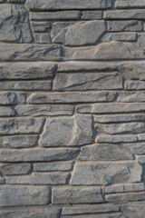 Fototapeta premium A close-up of a textured stone wall featuring a detailed pattern and rugged surface. This image is perfect for use in architectural designs, graphic resources, or as a background in construction-theme