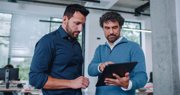 Busy men discussing about new business project or paths of improvement in middle of office building. Partnership concept.