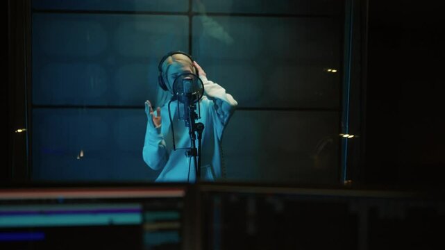 Female singer recording new pop song in professional record studio, portrait. Beautiful woman singing to microphone, star of popular record label, talented lady starting career in musical industry