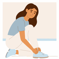 A woman is sitting on the floor and putting on her shoes. She is smiling and she is in a good mood