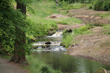 A Woodland River Flowing Over Some Small Waterfalls.