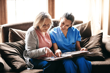 Senior, woman and caregiver with photo album on sofa for memories, nostalgia and remember with...