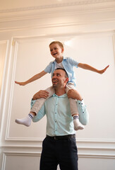 Little boy has fun with his father, who carries him while they spend time together at home. Father's Day concept, family, love. I feel happy in my dad's arms. Selective focus. Vertical image.