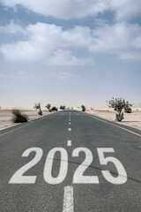 Text "2025" on an asphalt road between desert dunes represents future planning, challenges, and the path to business goals ahead