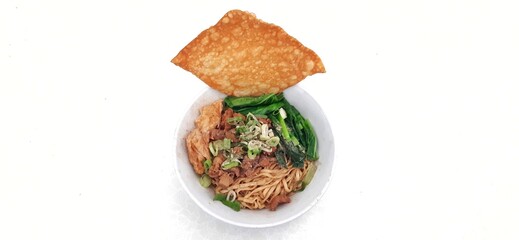 Chicken noodle or mie ayam with fukien, fried dumplings and vegetables served on bowl isolated on white background. Popular street food in Indonesia