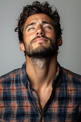 Fototapeta premium Smiling man in plaid shirt with eyes closed standing against gray background