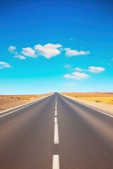 Naklejka premium Open Road Ahead: A long, straight highway stretches endlessly into the horizon, promising adventure and freedom. The clear blue sky and fluffy white clouds above hint at a journey filled with possibil