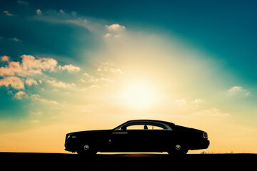 Naklejka premium Lone Car Silhouetted by the Setting Sun