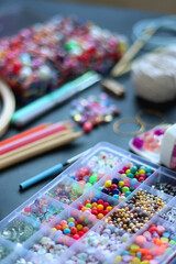 Colorful beads, coloring pencils, glitter, needles, string, hoop, tape and scissors on dark...