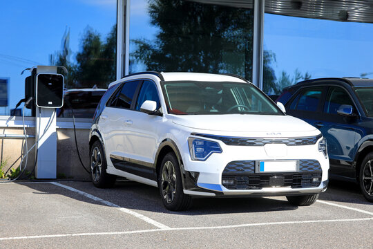 2024 white Kia Niro II battery electric crossover car parked next to battery charger at the dealership. 