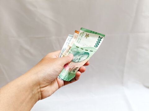 hand holding some Indonesian rupiah cash banknote or money paper for paying. paying concept, finance concept.
