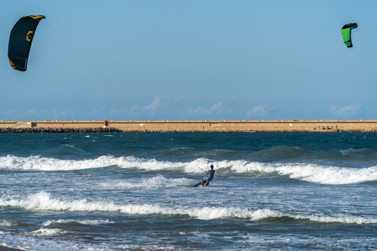 A young man kitesurfing at sunset in the sea.
