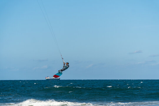 A young man kitesurfing at sunset in the sea.