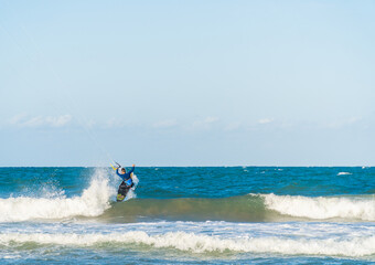 A young man kitesurfing at sunset in the sea.
