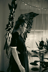 Woman with black feathered wings in monochrome interior setting