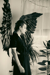 Monochrome angelic figure with black wings and indoor plant decor