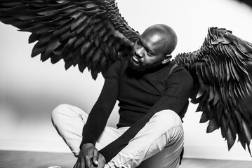 Man with majestic black wings sitting in thoughtful pose