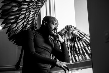 Contemplative man with dramatic wings in monochrome setting