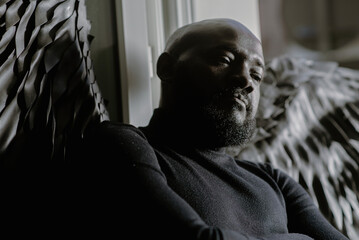 Contemplative man with black wings in dim light