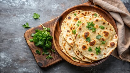 Freshly made chapati Indian flatbreads topped with parsley, captured in a top view with copy space