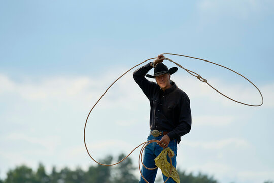 Cowboy performing a lasso trick under a cloudy sky.