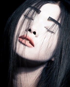 Close-up portrait of a woman with dark hair covering half her face, with eyes closed and a slight pout.