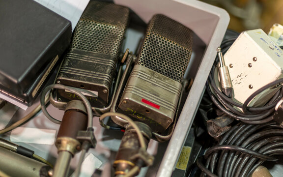 Two vintage RCA microphones with attached cables nestled among audio equipment.
