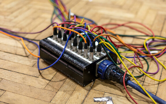 A close-up of a complex electronic device with colorful wires on a wooden floor.