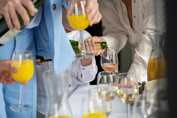 Waiter pouring champagne into glasses at a social event with guests holding drinks.