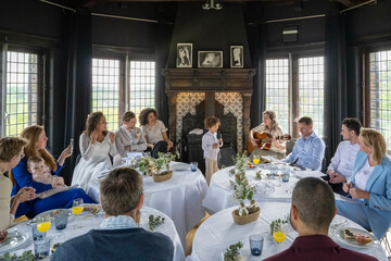 Guests enjoy live guitar music at an elegant indoor event with a dining setup and cozy ambiance.