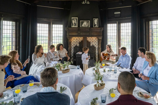 Guests enjoy live guitar music at an elegant indoor event with a dining setup and cozy ambiance.