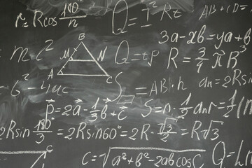 with math formulas written in white chalk on black board background