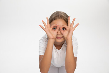 Front portrait of a fuuny teen girl,  looking through fingers, isolated white background.