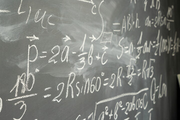 with math formulas written in white chalk on black board background