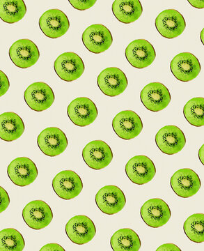 Seamless pattern of sliced kiwi fruit on a light green background.