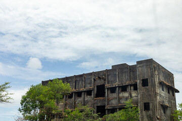Abandoned building is nestled among green trees under a clear blue sky