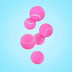 Many pink tennis balls in air on light blue background