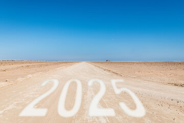 2025 is written on a track leading into the desert under a clear blue sky, Concept of future planning, challenges, and business goals, copy space in the blue sky
