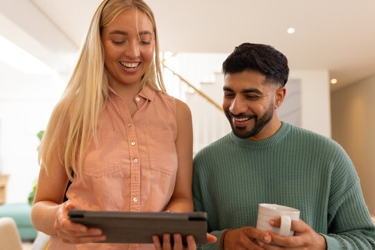Smiling friends using tablet and drinking coffee, enjoying time together indoors