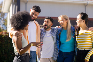 Group of young friends standing together outdoors, smiling and talking