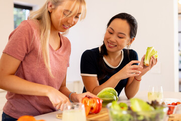Cooking fresh vegetables, diverse friends preparing meal together in kitchen, smiling and enjoying