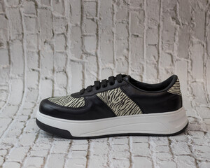 Elegant sneaker in eco-leather, black with animal print motifs, left view, for casual use