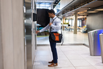 Fototapeta premium Businessman with briefcase pressing elevator button in modern office building